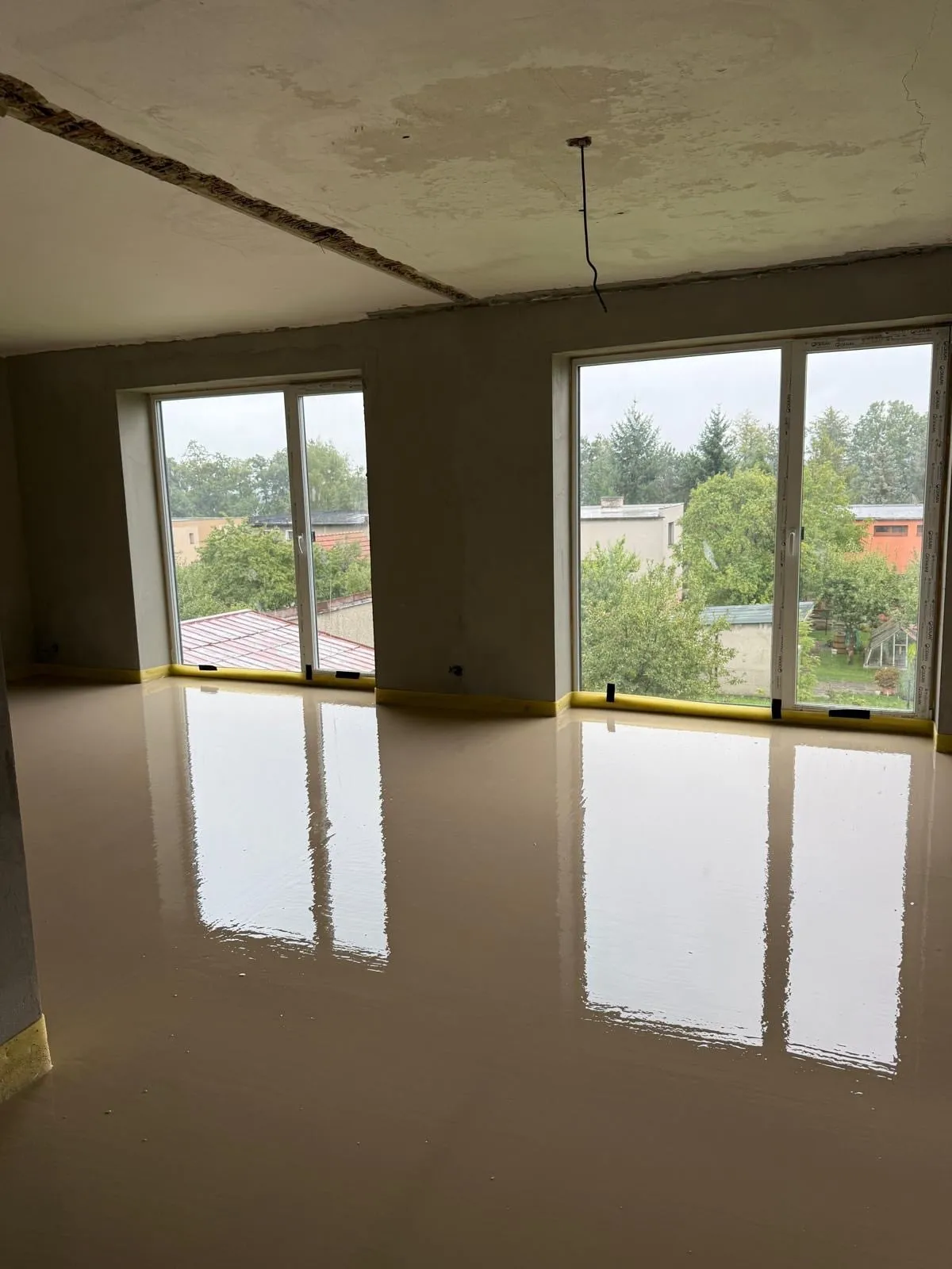 Obývací pokoj před rekonstrukcí: čerstvě litý potěr, neomítnutý strop, holé stěny